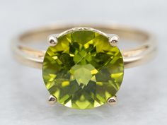 an oval cut green gemstone sits on top of a gold band