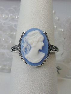 Cameo Ring Edward Design#70 Custom Made Here we have an Edwardian reproduction ring in sterling silver filigree with a variety of resin cameo options, choose from a black, light blue, or light pink lady silhouette, or an deep-orange daisy flower, or a light blue Bell flower. These beautiful cameos measure 14mm in length and 10mm in width. This ring also sits 7mm off the finger. The inside of the band is marked 925 for solid sterling. Notice the beautiful leaf and floral design of the filigree se Fine Jewelry Silver Intaglio Rings, Round Intaglio Jewelry, Fine Jewelry Silver Rings With Intaglio, White Gold Intaglio Rings For Wedding, Engraved Heirloom Rings, Victorian Sterling Silver Jewelry With Intaglio, Antique Sterling Silver Intaglio Jewelry, Victorian Sterling Silver Intaglio Jewelry, Vintage Silver Ring With Intaglio