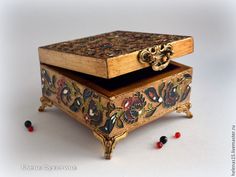 an ornate wooden box with floral designs on the lid and sides, surrounded by beads