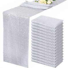 a stack of white napkins sitting on top of a table next to a bouquet of flowers