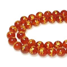 red beads with gold designs on them are shown in front of a white background,