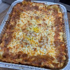 a square casserole dish with cheese on it sitting on top of a wooden table