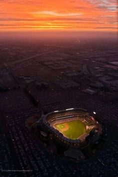 an aerial view of a baseball stadium at sunset with the sun setting in the distance