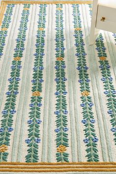 a white chair sitting on top of a rug next to a table with a drawer