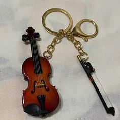 a violin keychain with a pair of scissors attached to it, sitting on a white sheet