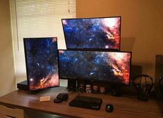 three computer monitors sitting on top of a wooden desk