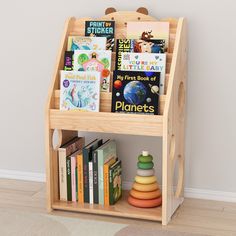 a wooden book shelf with books and toys on it in front of a white wall