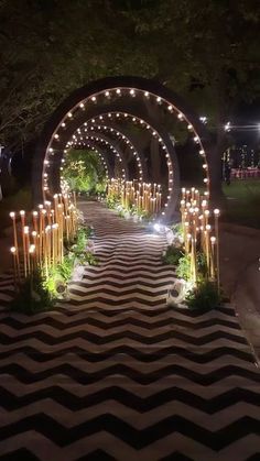 an outdoor walkway decorated with candles and greenery for a night time wedding or special event