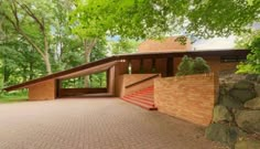 a brick driveway with steps leading up to a house in the woods on a sunny day