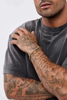 a man with tattoos on his arm posing for the camera while wearing a grey shirt