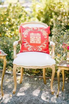 a chair with a red pillow sitting on top of it next to two small tables