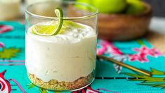 a dessert with limes and whipped cream in a glass on a blue tablecloth