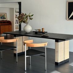 a dining room table with two chairs and a vase