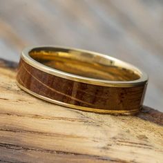 a wooden ring sitting on top of a piece of wood with gold inlays