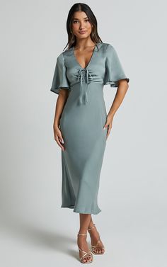 Get ready to turn heads in the Nicholla Midi Dress! This stunning A-line dress features a ruched front and angel sleeves that add an ethereal touch. Made from luxurious satin polyester, this dress has a V-neckline and falls perfectly at midi length for a flattering silhouette. Whether you're attending a cocktail party or a wedding as a guest, the sage green color of this dress will make you stand out from the crowd. With its short sleeves and comfortable fit, the Nicholla Midi Dress is both styl Summer Satin Dress With Gathered Sleeves, Spring Satin Midi Dress With Gathered Sleeves, Satin Ruched V-neck Midi Dress, Satin V-neck Dress With Gathered Sleeves, Satin V-neck Midi Dress With Draped Sleeves, V-neck Satin Dresses With Gathered Sleeves, Elegant Dress With Gathered Neckline And Flutter Sleeves, Spring Satin Dress With Flutter Sleeves, Elegant Ruched Satin Dress For Brunch