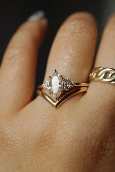 a woman's hand with two gold rings on it and a white diamond in the middle