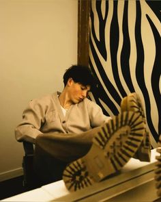 a man sitting in front of a zebra print wall