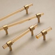 four gold colored handles and knobs on a white surface