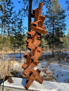 a metal sculpture sitting on top of a cement block in front of snow covered ground