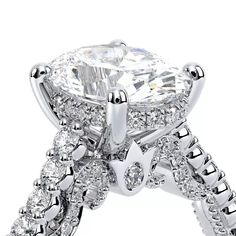 an engagement ring with a large diamond center surrounded by smaller round cut diamonds on the sides