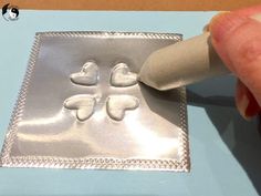 a person is using a stamp to make a heart design on a piece of metal