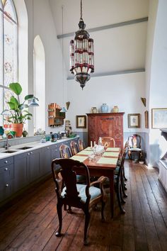 a dining room table with chairs and a chandelier hanging from the ceiling above it