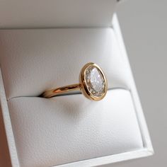 a gold ring with a white diamond in it's center sits inside a box