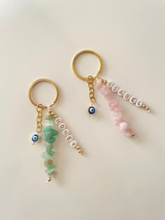 two keychains with beads and charms on them sitting next to each other in front of a white surface