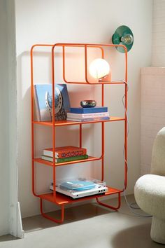 an orange shelving unit with books on it and a lamp next to the shelf