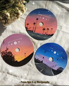 three discs sitting on top of a white cloth covered table next to a vase with flowers