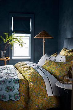 a bed with yellow and green comforters in a dark room next to a window