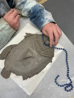 a man is making an octopus sculpture out of clay on a sheet of white paper