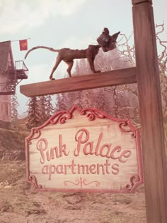 a sign for pink palace apartments with a cat standing on it's back end