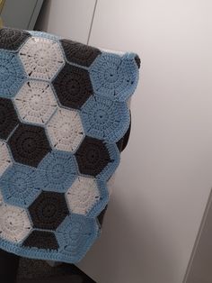 a crocheted blanket is hanging on the back of a chair in a room