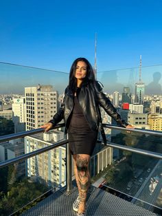 a woman with tattoos standing on top of a building