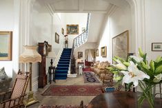 a living room filled with lots of furniture and flowers on top of a wooden table