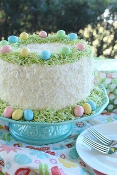 a cake with grass and eggs on it sitting on top of a table next to plates