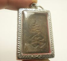 a person is holding up a silver pendant with an image on it's side