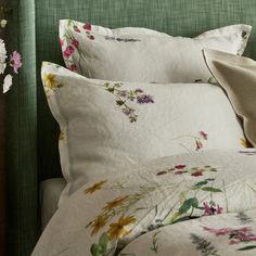 a green headboard with flowers on it and white linens in the bedding