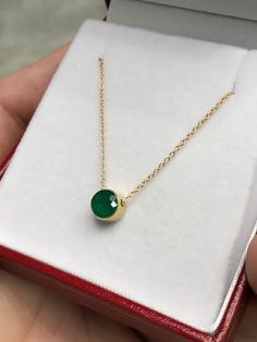 Featured here is a stunning, round Colombian emerald pendant in fine 14k yellow gold. Displayed in the center is a medium-green emerald accented by a simple bezel gold mount. The earth mined, green emerald has a desirable lush green color. This emerald is 100% earth mined and is not perfect! Gorgeous flaws are seen within the stone, embrace uniqueness! The chain is attached to this piece, non-removal. Total Carat Weight: 0.90cts Setting Style: Bezel Setting Material: 14K Yellow Gold Main Stone: Gold Emerald Pendant Necklace With Bezel Setting, Elegant Emerald Necklace With Round Pendant, Elegant Emerald Round Pendant Necklace, Elegant Emerald Birthstone Necklace With Round Pendant, Elegant Gold Emerald Necklace, Formal Round Emerald Necklaces, Fine Emerald Necklaces With Bezel Setting, Elegant Emerald Pendant Necklace With Bezel Setting, Gold Dainty Emerald Necklace