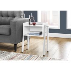 a white end table sitting on top of a wooden floor next to a gray couch