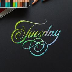 the words tuesday written in chalk on a blackboard with crayons next to it