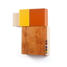 a piece of wood with different colored blocks on the top and bottom, sitting on a white surface