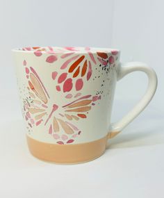 a coffee cup with pink, orange and white designs on the outside is shown in front of a white background