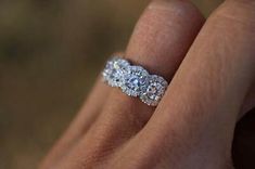 a woman's hand with a diamond ring on top of her finger and an engagement band in the middle