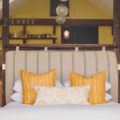 a bed with yellow and white pillows in a room that has an open roof area