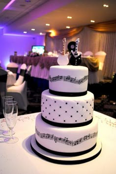 a wedding cake with musical notes on it and wine glasses sitting next to the cake