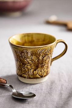 a coffee cup and spoon sitting on a table