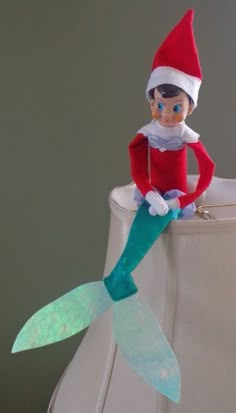 an elf is sitting on top of a trash can with a mermaid tail attached to it