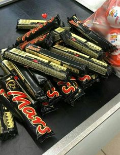 a pile of chocolate bars sitting on top of a counter next to a bag of candy